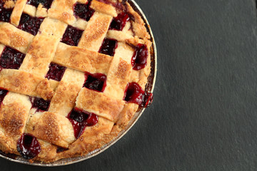 Traditional delicious cherry pie with a lattice of dough on a black graphite background with free space for text.  Holiday treat old fashioned retro american sweet pie
