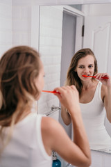 adult beautiful woman brushing his teeth in the bathroom in the morning