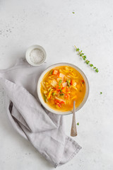 View from above on spring vegetable soup with chicken stock for one person on white table.