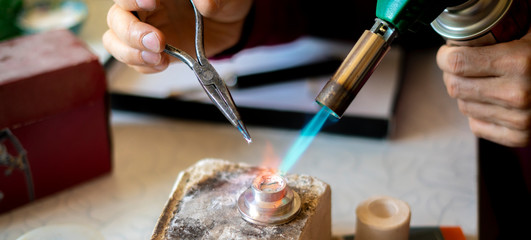 close up photo of factory worker melting maetal with gas burner b