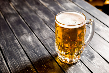 A mug of fresh light beer on a bar wooden table. Top view. 