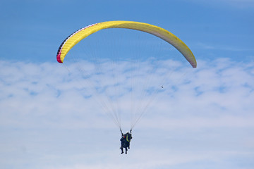 Tandem paraglider flying yellow wing