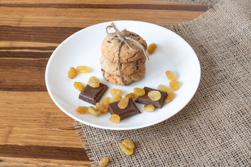 Homemade coconut  cookies on white plate . Raisins and slices of milk chocolate.