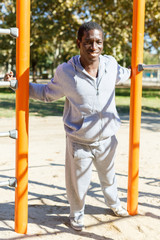 Fototapeta premium Athletic african american male performs warm-up exercises at chin-up bar
