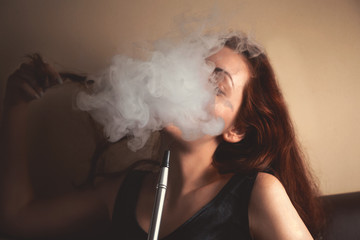 Sexy young woman Smoking a hookah and behind a cloud of smoke or steam can not see the face