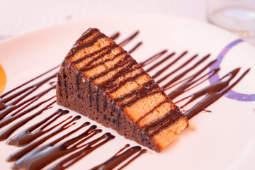 Portion of sponge cake with chocolate on plate