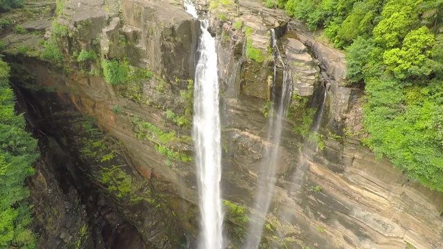 Drone shot of the Bambarakanda Falls, Sri Lanka, surrounded by bright green trees, on a cloudy and foggy day
