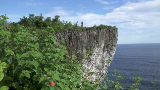 Young Romantic Couple Walking Holding Hands on a stunning high Karang Boma Cliff viewing the Ocean in Bali, Indonesia 