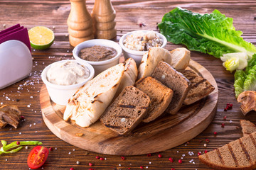 Assorted three types of bread with liver pate on a wooden board