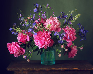 bouquet of peonies and irises in a vase on the table.