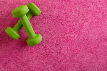Little green fitness dumbbells on pink background