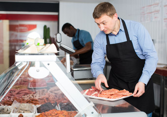 Two butchers arranging meat display