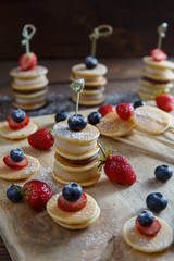Fruit, berry and pancake canapes on wooden table