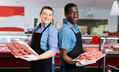 Fototapeta na wymiar Successful sellers of butcher store offering fresh raw meat steak cutlets