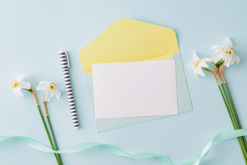 Mockup white wedding invitation and envelope with white daffodils on a blue background