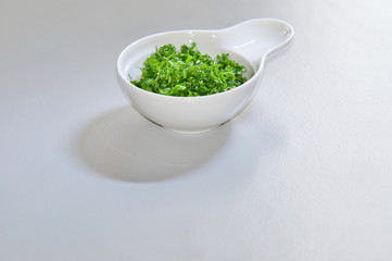 Ingredients for a healthy dish. Hacked parsley in a small ceramic bowl.