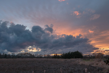 Dramatic storm clouds at sunset over marsh