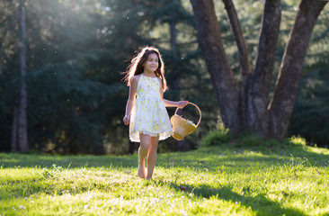 Little girl is walking holding woven basket with Easter pastel eggs