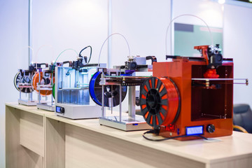 Automatic 3D printers in row during work at modern technology exhibition. 3D printing, additive...