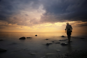 Fototapeta na wymiar landscape sunset on the sea, man on the lake shore at sunset, beautiful place nature, water and seashore, concept of waiting for loneliness