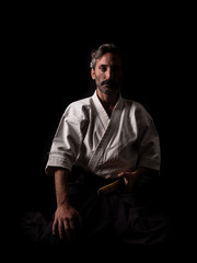 Aikido and Kenbudo practitioner with traditional costume on black background with katana sword