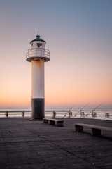 Old lighthouse of Nieuwpoort (Belgium) with three fishing rods at sunset