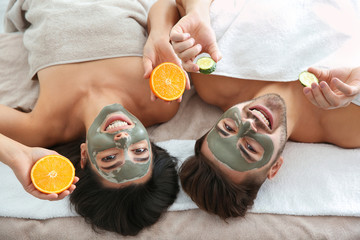 Happy couple enjoying facial treatment procedure in spa salon, above view