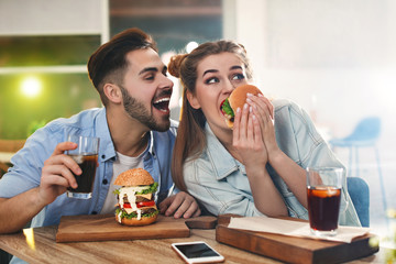 Happy young couple having lunch in burger restaurant