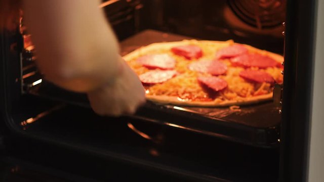 Woman or man put in the oven pizza for baking.