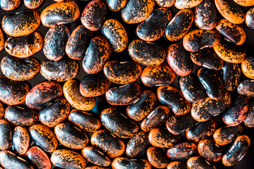 a heap of black-brown beans on black background