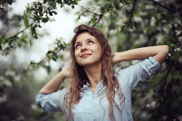 Fototapeta premium young adult girl enjoys smell of spring flowers apple