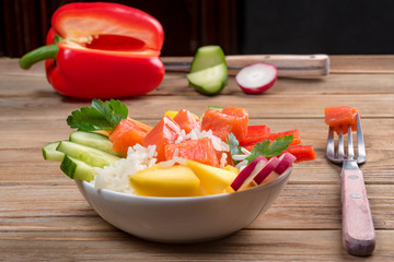 Poke salad from hawaii with and vegetables on wooden background. Close up. Soft focus. To prepare it just take rice, salmon and any vegetables.