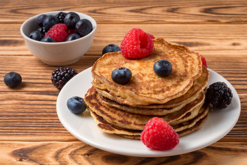Pancakes with blueberries and strawberries and cup of red juice on wooden background. Close Up. Soft focus.