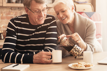 Loving senior woman pouring fresh tea to her husband's cup