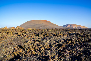 Spain, Lanzarote, Huge black field of lava surrounding colorful red volcanic mounts