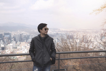 Fototapeta premium A man wearing sunglasses Black leather jacket And pale jeans Standing in the view point in winter
