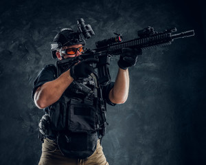 Special forces soldier holding an assault rifle with a laser sight and aims at the target.