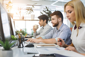 Young millennial people working on computers at coworking
