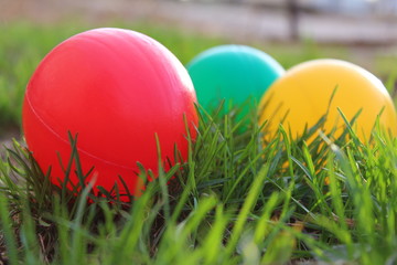 Fototapeta na wymiar three colored balls lying on the green grass