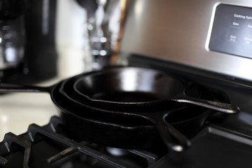 Cast iron skillets on a modern gas stove oven in a home.