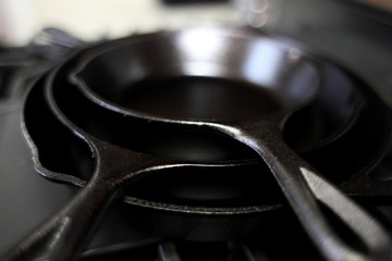 Cast iron skillets on a modern gas stove oven in a home.