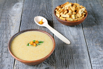 Chanterelle cream soup in a clay bowl on wooden background.