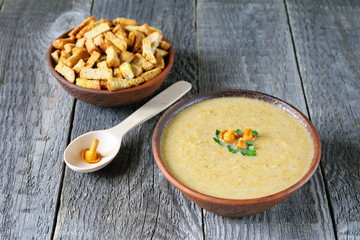 Chanterelle cream soup in a clay bowl on wooden background.