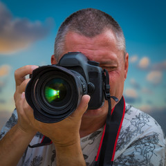 Ein Fotograf macht ein Foto mit einer Spiegelreflexkamera mit grüner Reflektion und blauem Himmel im Hintergrund
