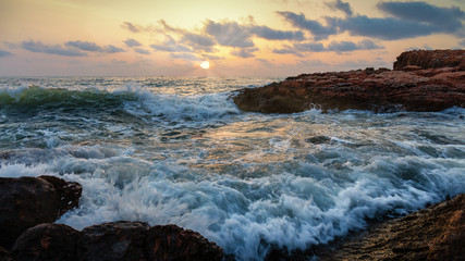 Shortly after sunrise, the seething waves beat against the rocky coast and the beach