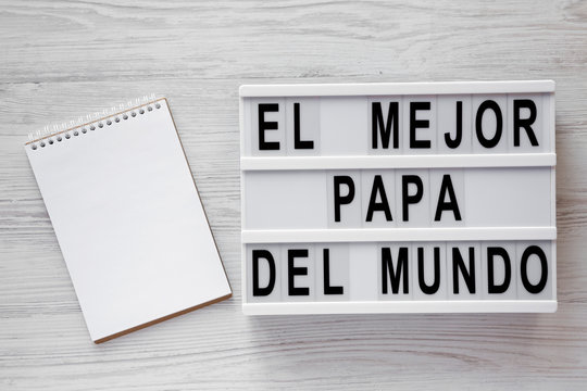 'El Mejor Papa Del Mundo' words on modern board, blank notepad over white wooden background, top view. Overhead, from above, flat lay. Father's day concept.