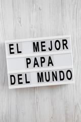 'El Mejor Papa Del Mundo' words on lightbox over white wooden surface, overhead view. Top view, from above, flat lay. Father's day.