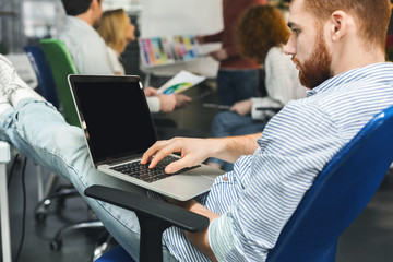 Focused millennial man browsing on laptop with blank screen