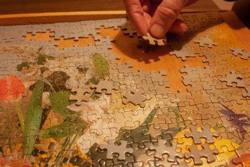 Fototapeta na wymiar A men puts a puzzle on the table. He love puzzles.