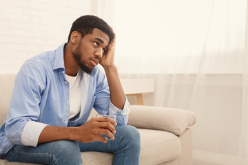 Young black man drinking alcohol at home feeling lonely